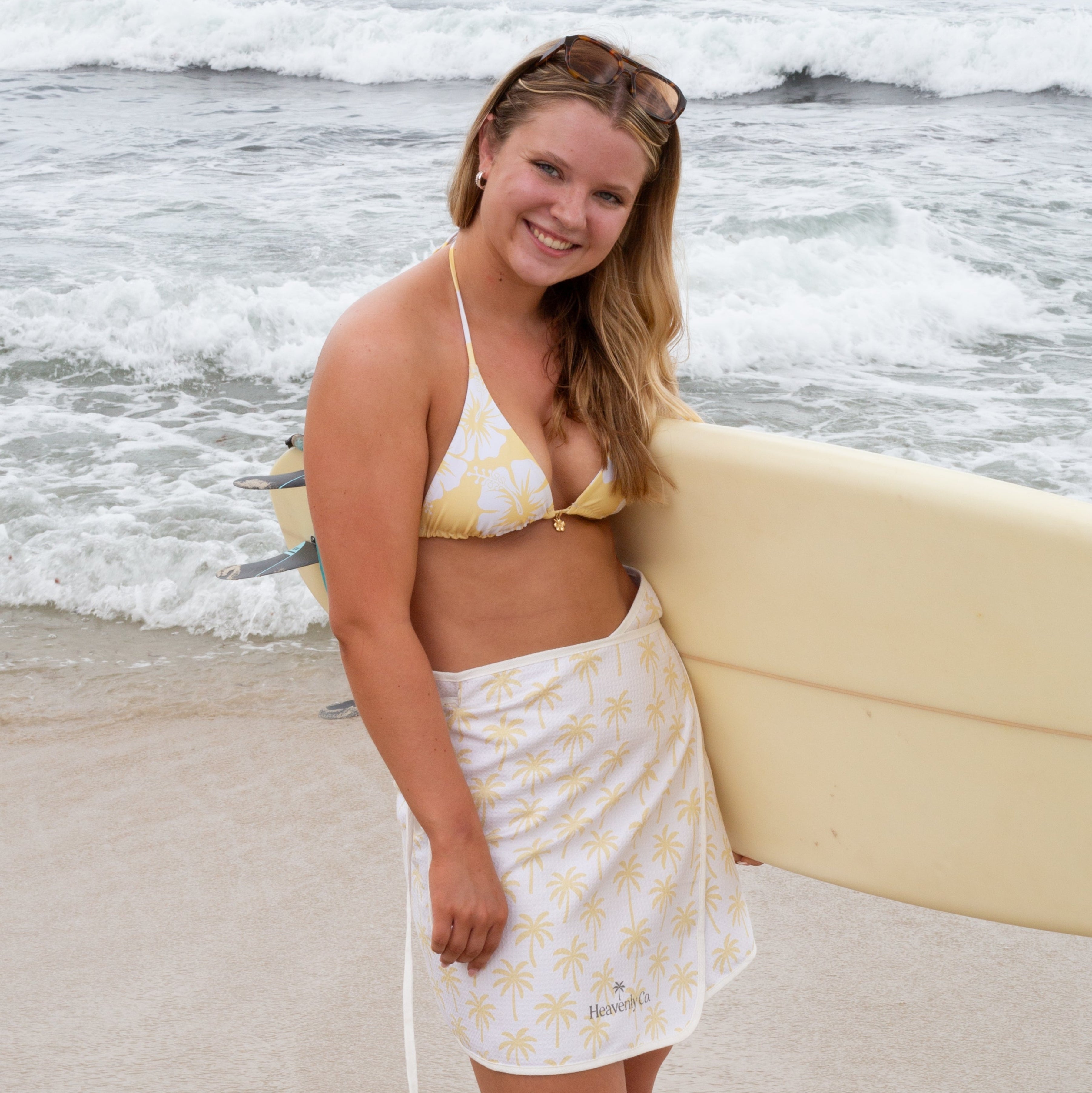 Woman holding a surfboard on a beach with ocean waves in the background