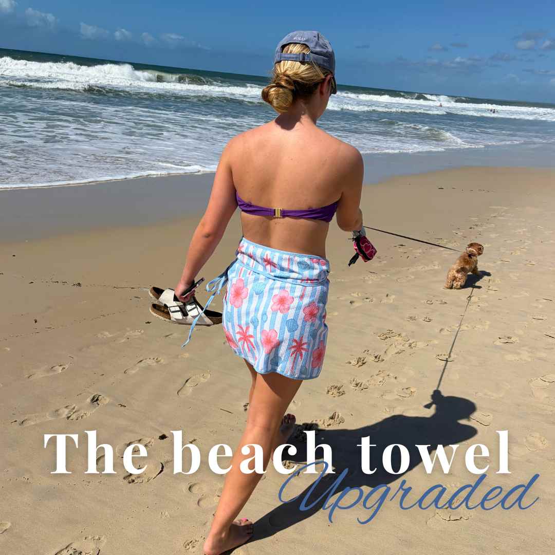 a girl walking on the each with her dog in a towel wrap skirt