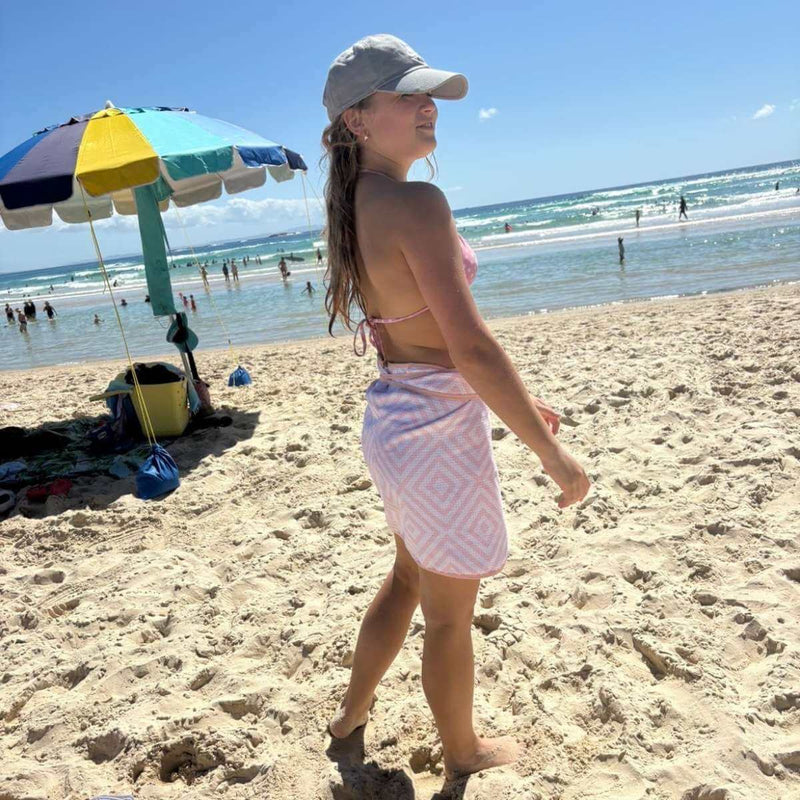 Woman walking on a beach with a colorful umbrella and ocean in the background