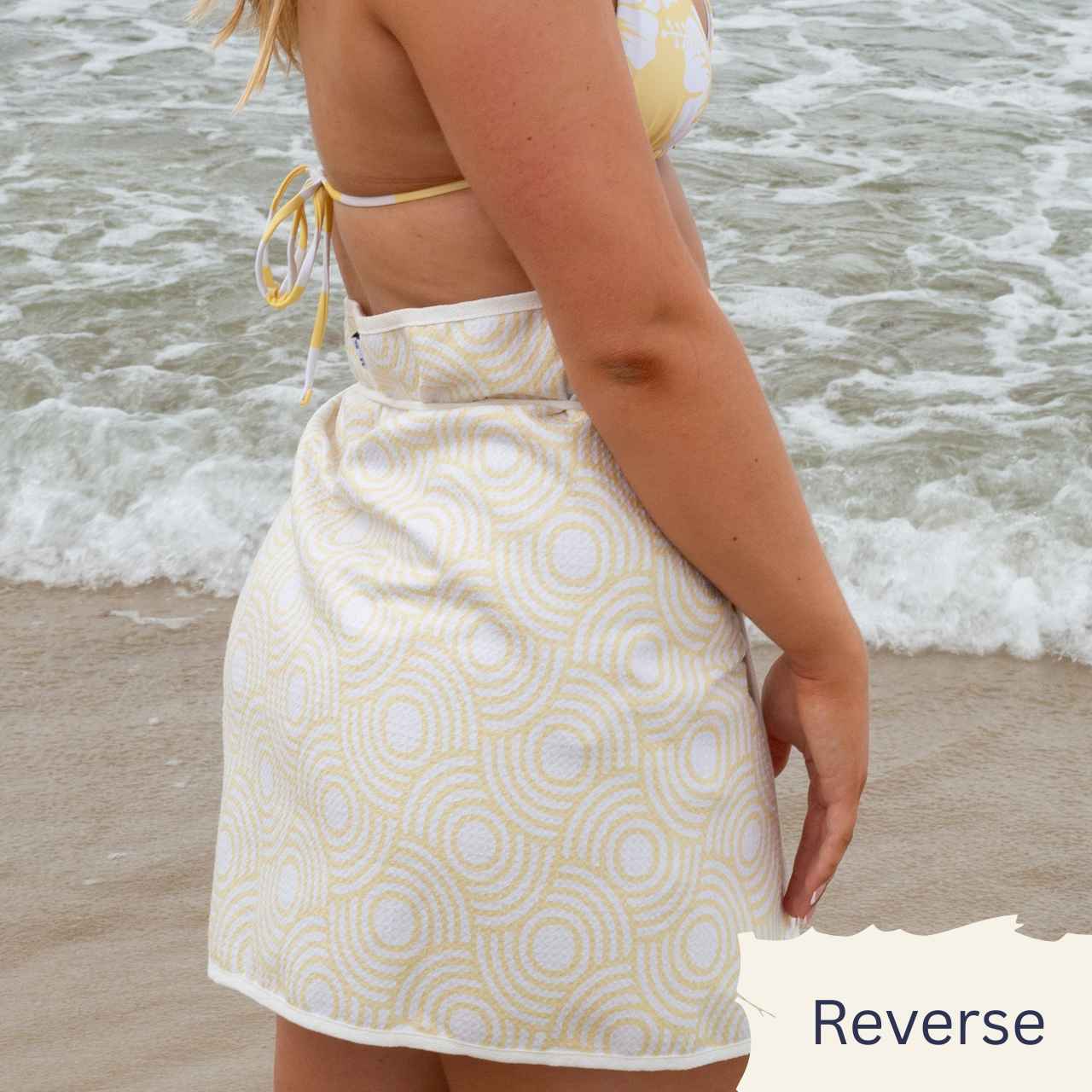Person wearing a patterned skirt with a beach background