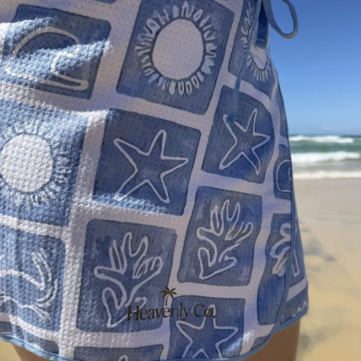 Blue and white patterned towel with beach scenery in the background